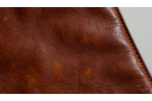 A close-up of full-grain aged leather showing rich natural patina, unique texture, warm tones, and natural creases formed through years of use and craftsmanship